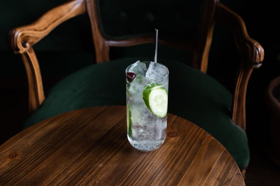 A spirit and mixer serve over ice, garnished with cucumber and cherry